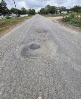 Pothole in the cracked asphalt of Spruce Street.